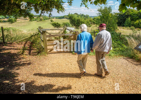 90 Jahre alter Mann nimmt seine Frau, die einen schweren Sehverlust auf dem Land in Wiltshire, in der Natur und weg von Ihrem Haus zu erhalten. Stockfoto