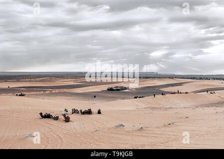 Sonnenaufgang in den westlichen Teil der Wüste Sahara in Marokko. Die Strahlen der Sonne durch die Wolken und heiligt den Campingplatz und Kamelen am Fuß Stockfoto