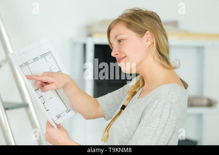 Weibliche Interior Designer bei Layout Pläne suchen Stockfoto