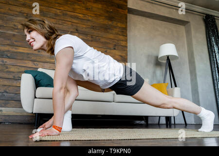 Junge blonde Frau zu tun stretching Yoga Übungen zu Hause. Gesunde Lebensweise. Entspannung und Wohlbefinden. Einklang mit sich.
