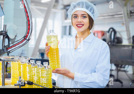 Junge schöne Mädchen in weißen Overalls im Werk für die Produktion von Sonnenblumen- und Olivenöl. Qualitätskontrolle in der Produktion. Stockfoto