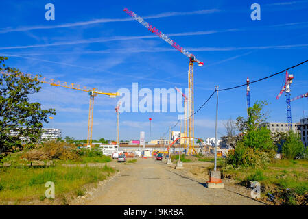 Mehrere Krane in Residential Apartment Complex Baustelle gegen den blauen Himmel mit Flugzeugen emission Streifen, Toulouse, Frankreich Stockfoto