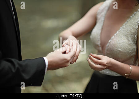 Erschossen Sie Moment, wenn der Bräutigam den Ring einerseits eine junge Braut bringt. Stockfoto