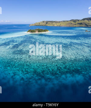 Aus der Vogelperspektive, einem idyllischen tropischen Insel ist durch ein gesundes Korallenriff im Komodo National Park, Indonesia umgeben. Stockfoto