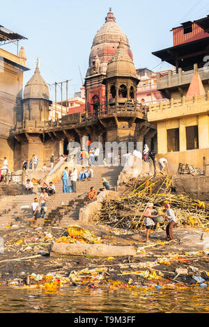 Varanasi, Indien, 27. März 2019 - Ganges mit Manikarnika Ghat, einem der bekanntesten hinduistischen Krematorium - eine Leiche wird durch das heilige Feuer verbrannt Stockfoto