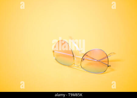 Horizontales Bild der weiblichen Stylische Sonnenbrille auf gelben Hintergrund. Heißer Sommer, Sonnenschutz, tropischen Reise, Urlaub, Strand, Optik conc Stockfoto