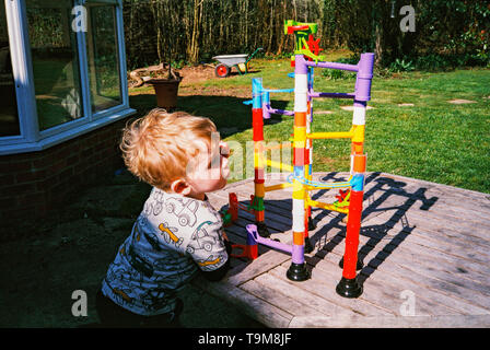 Zwei Jahre alte Junge spielt mit einem Spielzeug Kugelbahn. Medstead, Hampshire, England, Vereinigen Königreich. Stockfoto