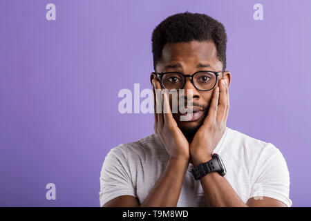 Portrait von überrascht, erstaunt afrikanischer Mann in Gläsern tragen weiße T-Shirt sein Gesicht berühren sich und die Handflächen und offenen Mund, in Schock, auf isolierte Stockfoto
