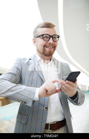 Positive mollig Mann über sms Denken Stockfoto