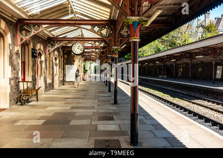 Eine Frau, die zu Fuß auf einem der Bahnsteige der Bahnhof Great Malvern, Malvern, Worcestershire, England, UK, das 1862 erbaut wurde. Stockfoto