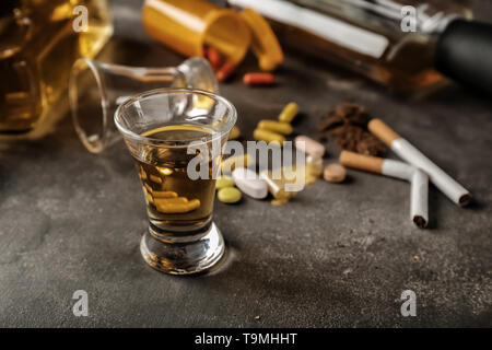 Glas Whiskey auf grauem Hintergrund. Konzept des Alkoholismus Stockfoto