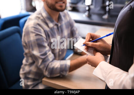 Junge Kellnerin, die einen Auftrag von Mann im Restaurant Stockfoto