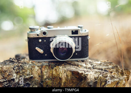 Von alten analogen Kamera Die Kamera steht auf einem Baumstumpf. Natur Hintergrund. Stockfoto