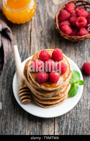 Leckere oat Pfannkuchen mit Himbeeren und Honig auf hölzernen Tisch Stockfoto