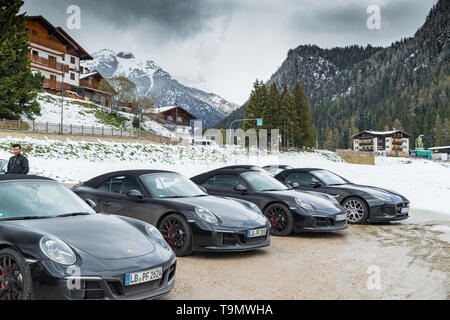 Italien, Trentino, die Gruppe der Luxus-Sportwagen macht einen Halt auf dem einige Dorf, schneebedeckte Feld auf dem Hintergrund, Porsche Stockfoto