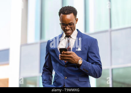 Outdoor ständigen Portrait eines schwarzen afrikanischen amerikanischen Unternehmen über ein Mobiltelefon mit einem Mann Stockfoto