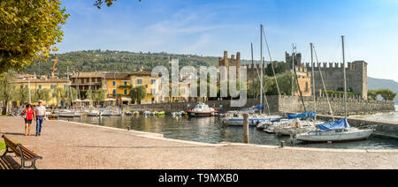 TORRI del Benaco, Gardasee, Italien - September 2018: Zwei Menschen zu Fuß auf der Seite der kleinen Hafen in Torri del Benaco am Gardasee. Stockfoto