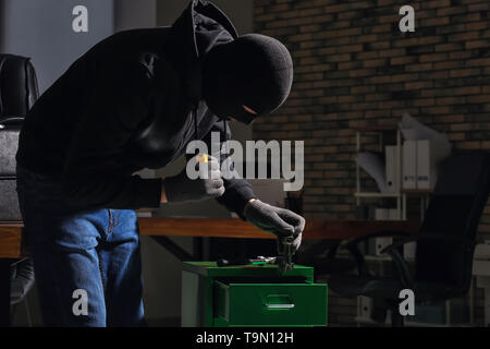 Männliche Dieb mit Taschenlampe im Büro Stockfoto