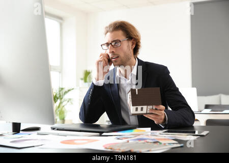 Junge Designer Gespräch am Handy am Arbeitsplatz im Büro Stockfoto