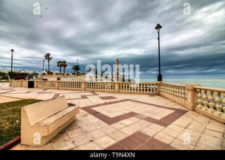 Promenade von Chipiona, in der Provinz Cadiz, Spanien, mit dem Leuchtturm im Hintergrund an einem stürmischen Tag Stockfoto