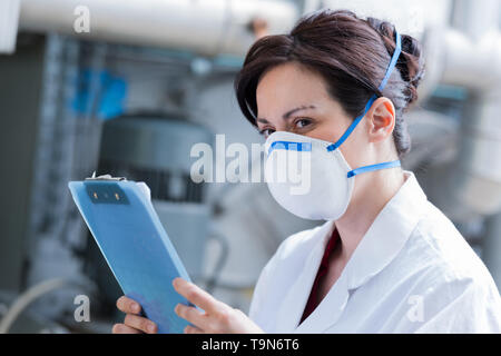 Geschäftsfrau durch das Tragen von schützender Maske holding Zwischenablage Stockfoto