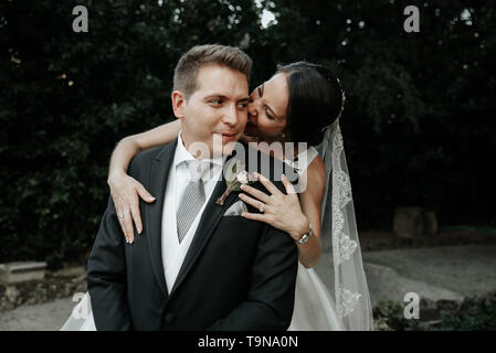 Frohe Braut beißt der Bräutigam von der ear. Spaß Hochzeit paar. Stockfoto
