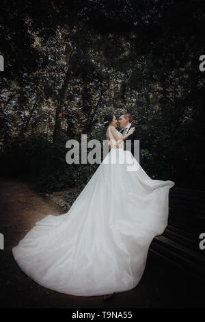 Braut und Bräutigam Hug im Park. Die Braut lehnte sich gegen den Bräutigam. Hochzeitstag Stockfoto