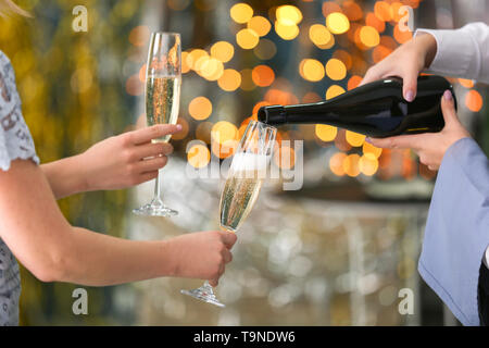 Kellnerin gießt Sekt aus der Flasche in eine Brille bei Party Stockfoto