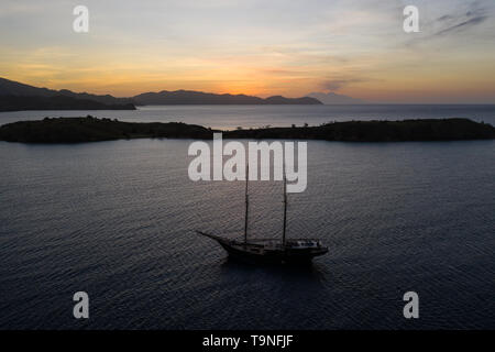 Ein traditioneller Pinisi schoner Segel bei Sonnenuntergang im Komodo National Park, Indonesia. Dieses tropische Gegend ist für ihre biologische Vielfalt bekannt. Stockfoto