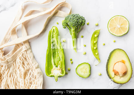 Frische Avocado, Kalk, Brokkoli, grüne Erbsen, Gurken, grüner Pfeffer, string Beutel. Flach. Essen Konzept. Grünes Gemüse liegen auf weißem Marmor backgrou Stockfoto