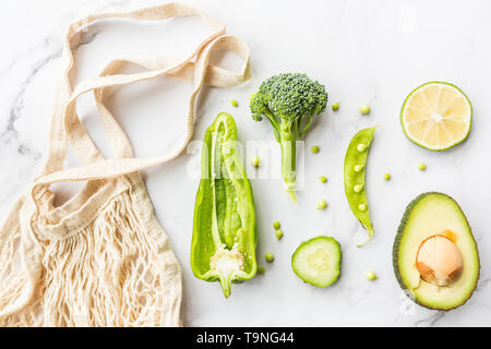Frische Avocado, Kalk, Brokkoli, grüne Erbsen, Gurken, grüner Pfeffer, string Beutel. Flach. Essen Konzept. Grünes Gemüse liegen auf weißem Marmor backgrou Stockfoto