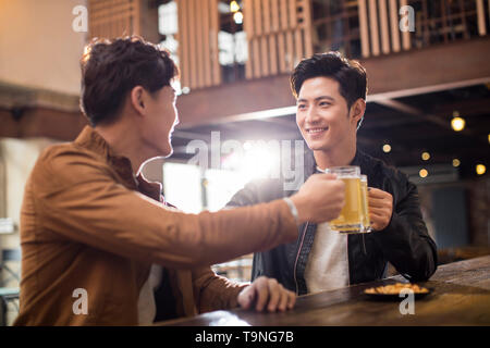 Glückliche junge Männer Toasten in bar Stockfoto