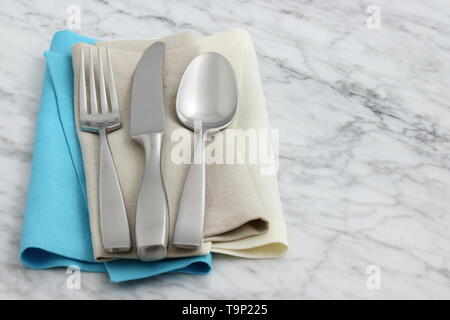 Trendiges und schönes Besteck set auf Leinen mit Hohlsaum Servietten und antiken Carrara Marmor gestalteten Stockfoto