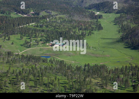 BLACK HILLS, South Dakota - 12. Juni 2014: Eine Luftaufnahme von einer abgelegenen Ranch House in eine grüne Wiese mit einer Wicklung Creek und Pinien in der blac Stockfoto