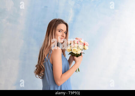 Schöne junge Frau mit Blumenstrauß auf farbigen Hintergrund Stockfoto
