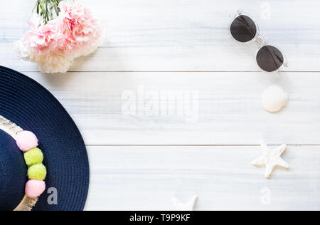Blick von oben auf die Summer Blue weibliche Hut mit Sonnenbrille und Shell und Star fisch Dekoration auf weißem Holz Tisch. Sommer Urlaub Stockfoto