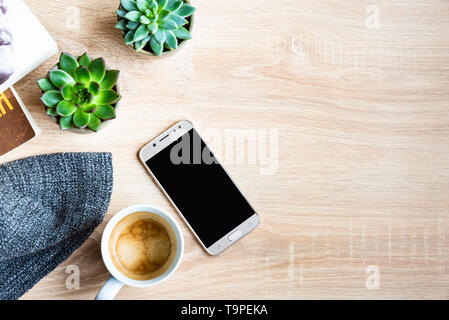 Blick von oben auf die gemütliche Szene. Bücher, Wolldecke, Tasse Kaffee und sukkulenten Pflanzen über Holz- Hintergrund. Kopieren Sie Platz. Stockfoto