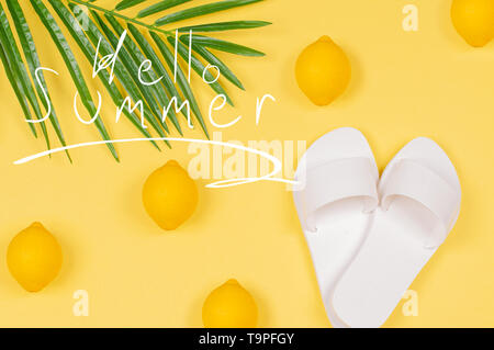 Hallo Sommer Text auf gelbem Hintergrund mit Zitrone, Sandalen und grünen tropischen palm leaf. Strand Zubehör Stockfoto