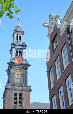 Close-up auf dem Turm der Westerkerk Kirche in Jordaan, Amsterdam, Niederlande, mit einem traditionellen Gebäude im Vordergrund. Stockfoto