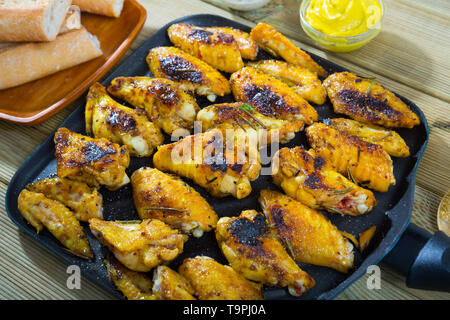 Crispy Fried Chicken Wings auf schwarz Grillpfanne mit cremiger Senfsauce Stockfoto