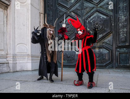 Eine maskierte Person in eine beängstigende kreative Kostüm und ein weiteres in einem Harlekin Kostüm, das Feiern der Venezianischen Karneval Stockfoto