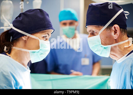 Seitliche Sicht auf zwei Chirurgen in Gespräch Stockfoto