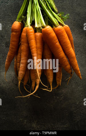 Nantes Karotten auf rustikalen dunklen Hintergrund. Frische organische Superfood Gesund Essen Konzept und Diabetes zu kontrollieren. Stockfoto