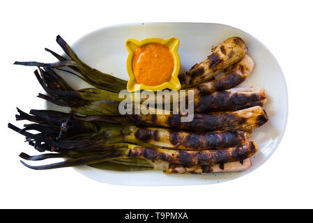 Blick von oben auf die gegrillten calcots traditionell serviert mit romesco Sauce. Nationale katalanischen Wintergericht. Auf weissem Hintergrund Stockfoto