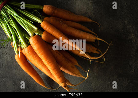 Nantes Karotten auf rustikalen dunklen Hintergrund. Frische organische Superfood Gesund Essen Konzept und Diabetes zu kontrollieren. Stockfoto