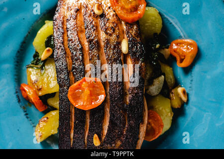 Knusprige Haut gebratener Lachs mit Gemüse auf Meer blaue Platte Stockfoto