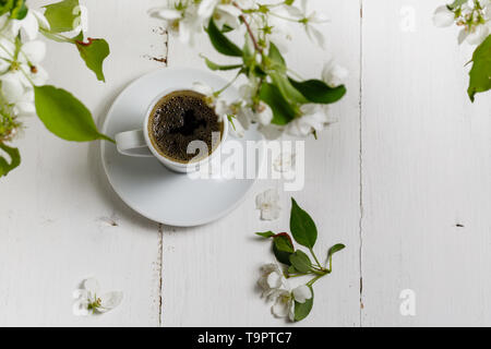 Der Frühling noch leben. Tasse Kaffee mit Apple tree Blumen und Blüten von Blumen auf weißem cafe Tisch draußen im blühenden Garten Stockfoto