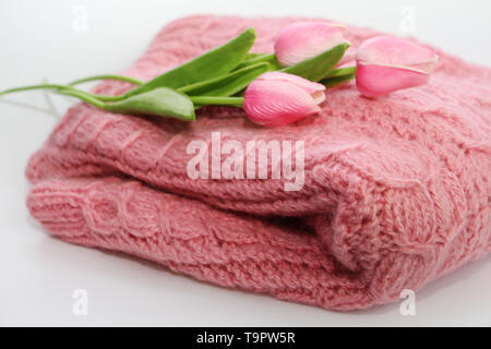 Ein warmes Rosa Strickpullover liegt auf einem weißen Hintergrund. Auf dem Pullover ist sichtbar Textur von einem schönen Muster. Pullover ist kompliziert. Auf der s Stockfoto