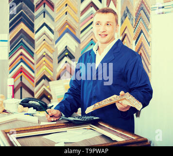 Portrait von froh russischen Mann Verkäufer arbeiten mit Bilderrahmen im Atelier Stockfoto