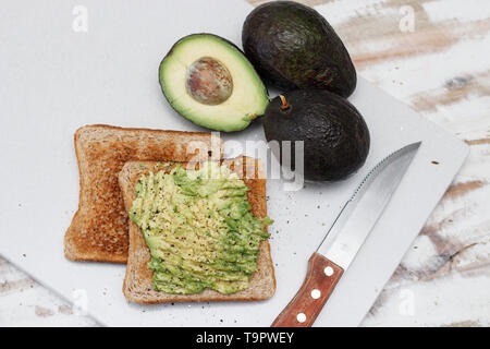 Guacamole auf Toast mit Messer und Avocados Stockfoto